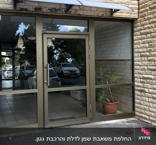 כניסה לבניין עם דלת זכוכית וצמח בעציץ